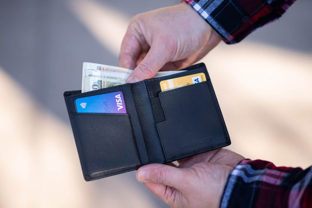 A man getting bills on her wallet with some cards on it