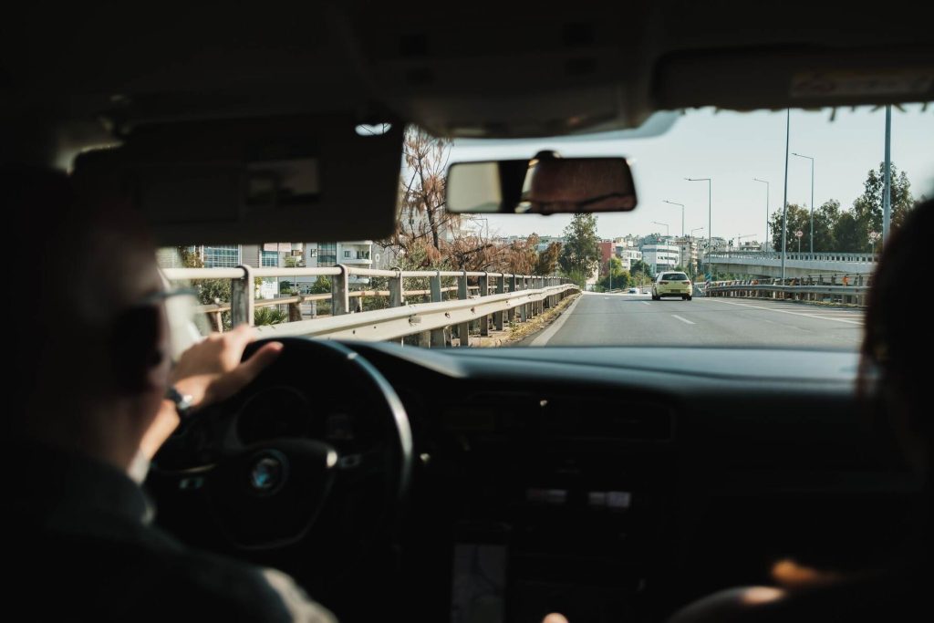 An adult driving his car showing the front view of the road