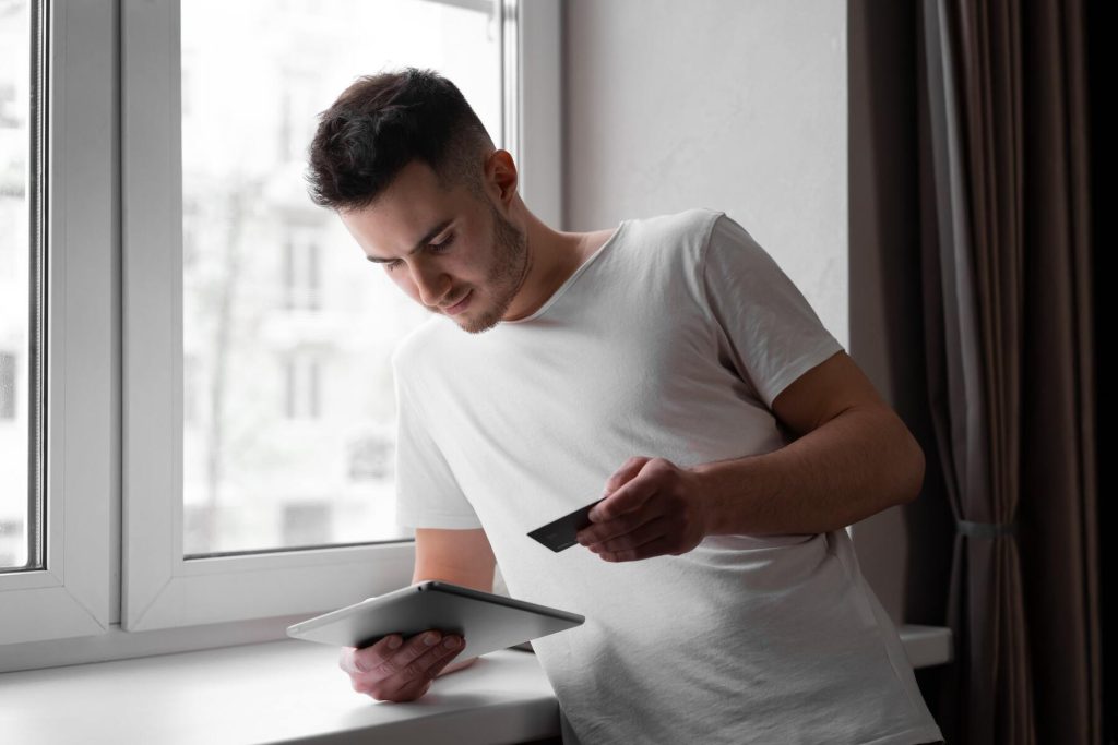 A man using his iPad while holding his credit card