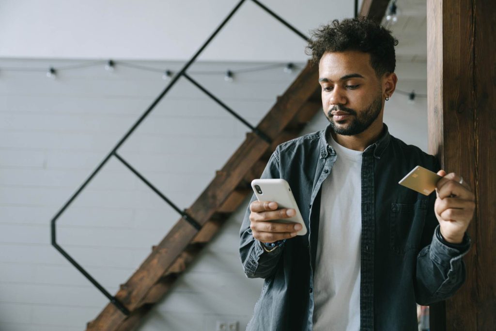 A man holding her credit card while scrolling on her phone