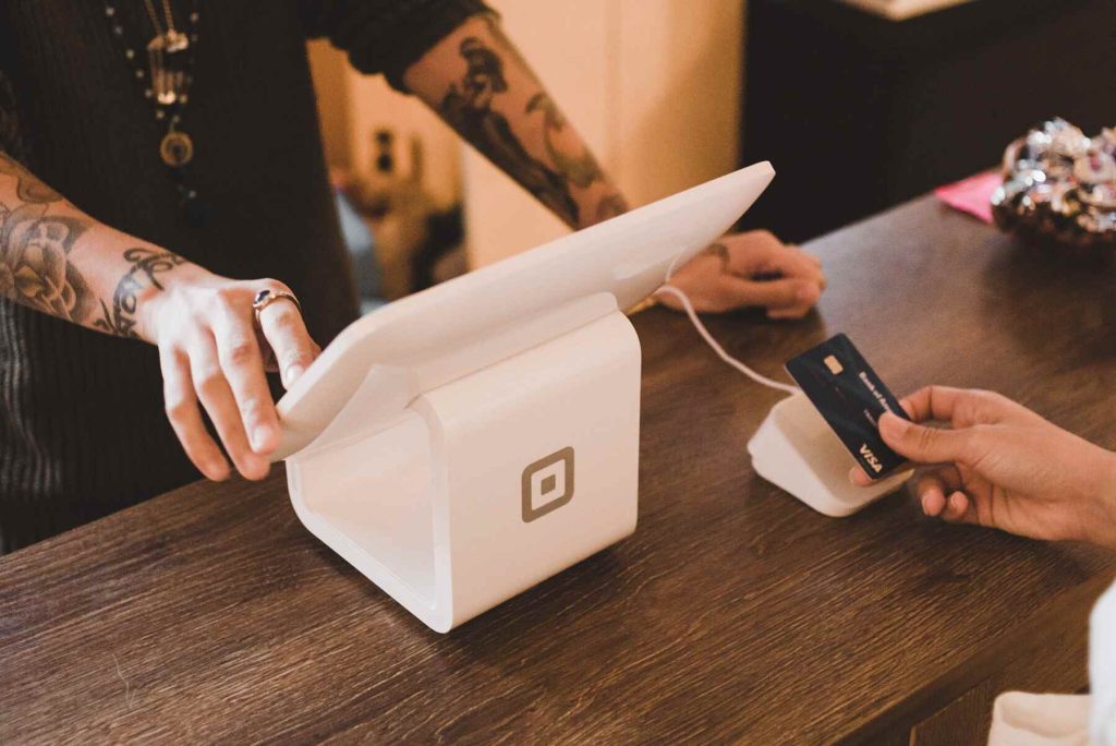 A man in front of a monitor and the other person is putting the credit card on a card reader