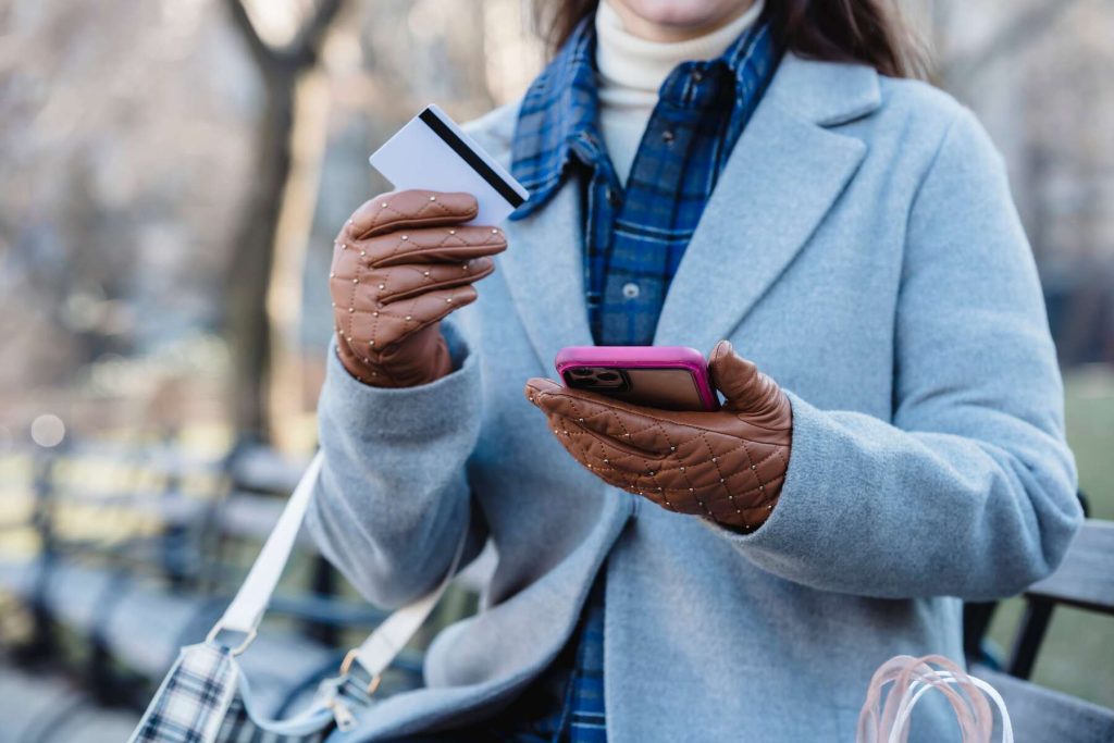 A woman wearing holding her phone and credit card