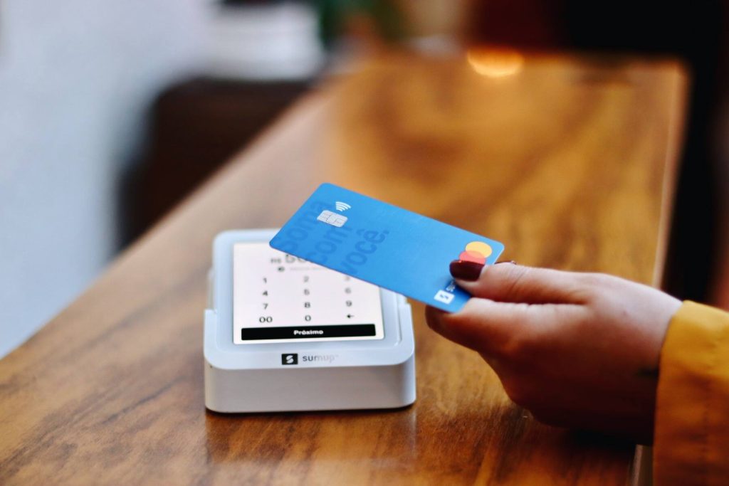 A woman showing her credit card with a white card reader