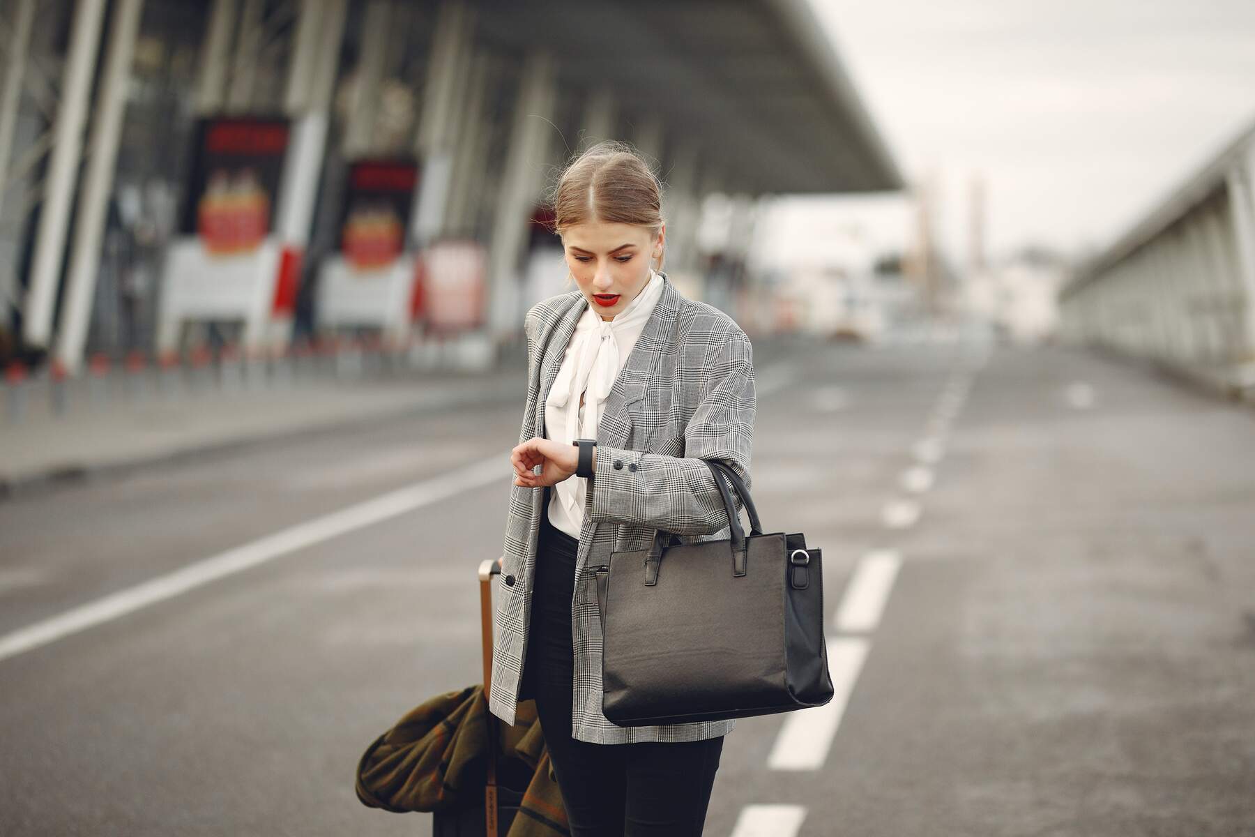 A woman standing outdoor while looking on her watch with a slightly shocked face