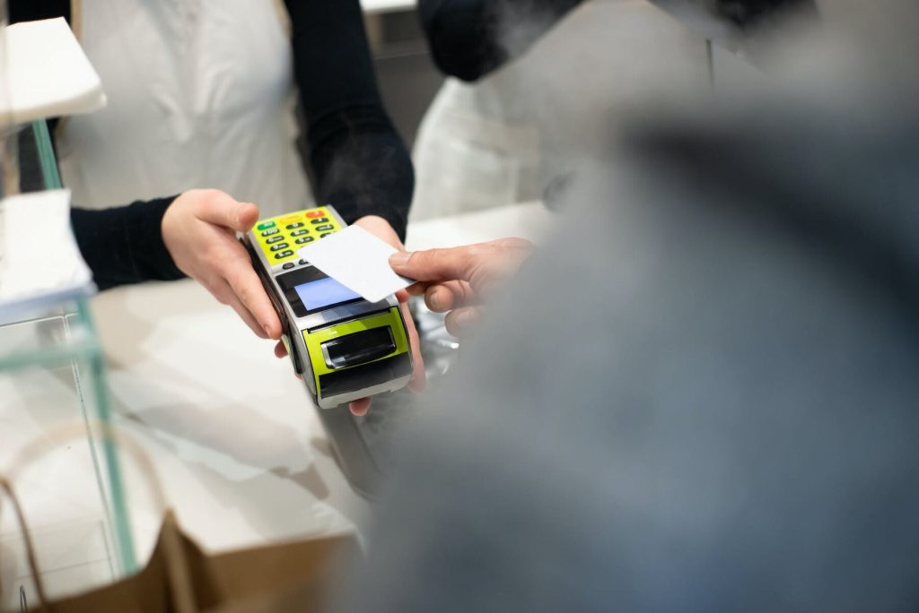 A man is paying using his credit card on a card reader held by a woman