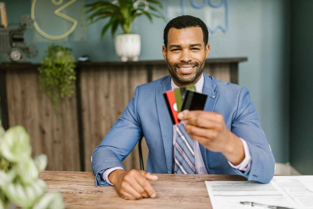 A man in a suit holding three credit cards