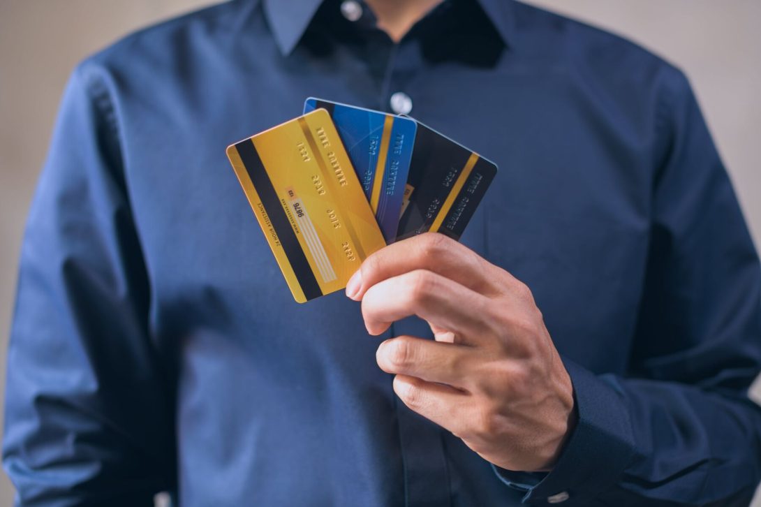 A man holding three different credit cards
