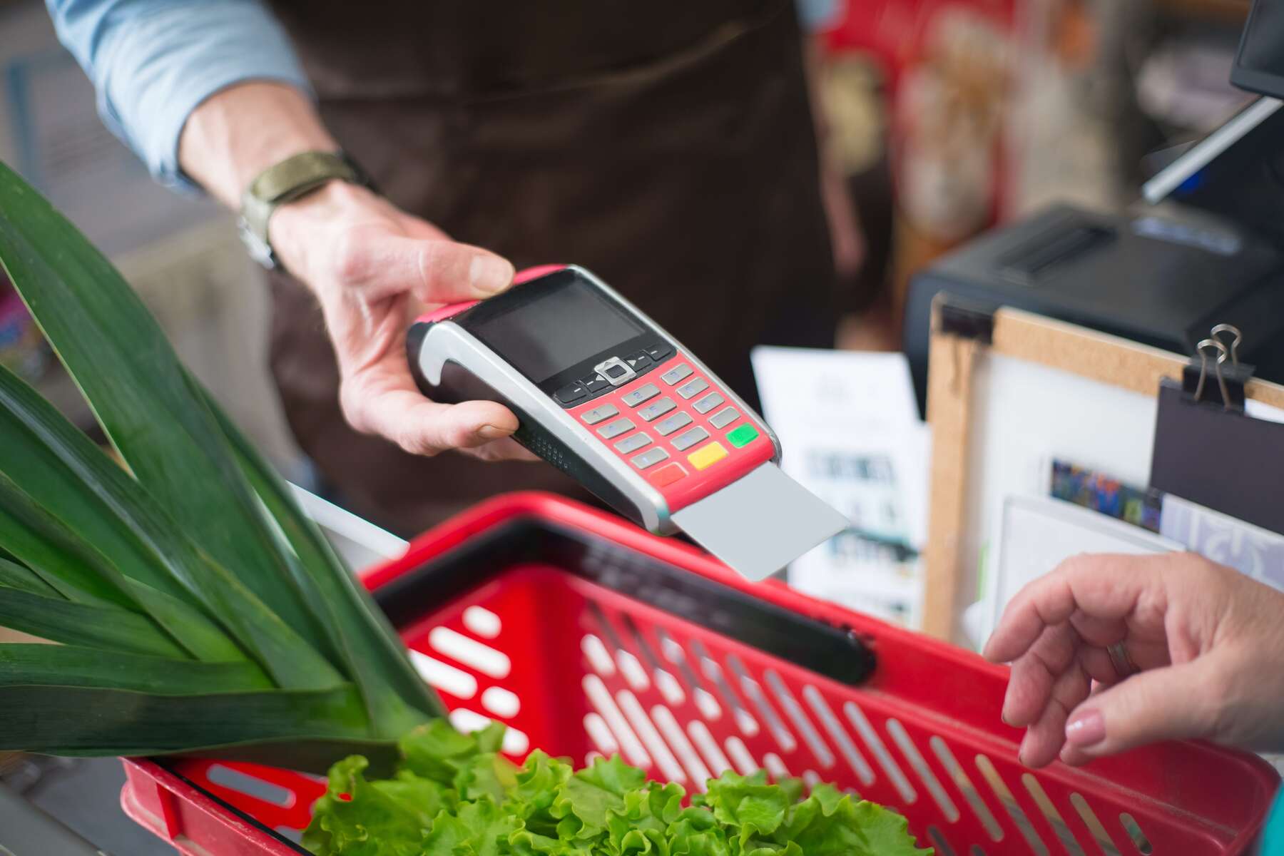 A cashier on a grocery store holding a terminal payment with a card in it
