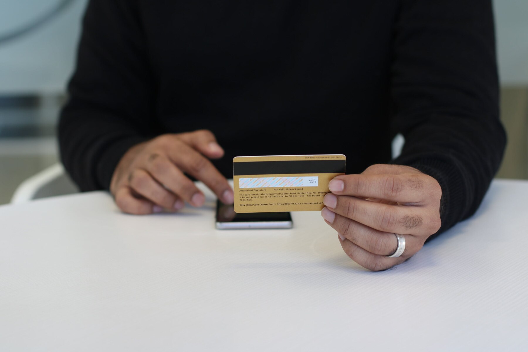 A man holding a yellow credit card while tapping his phone