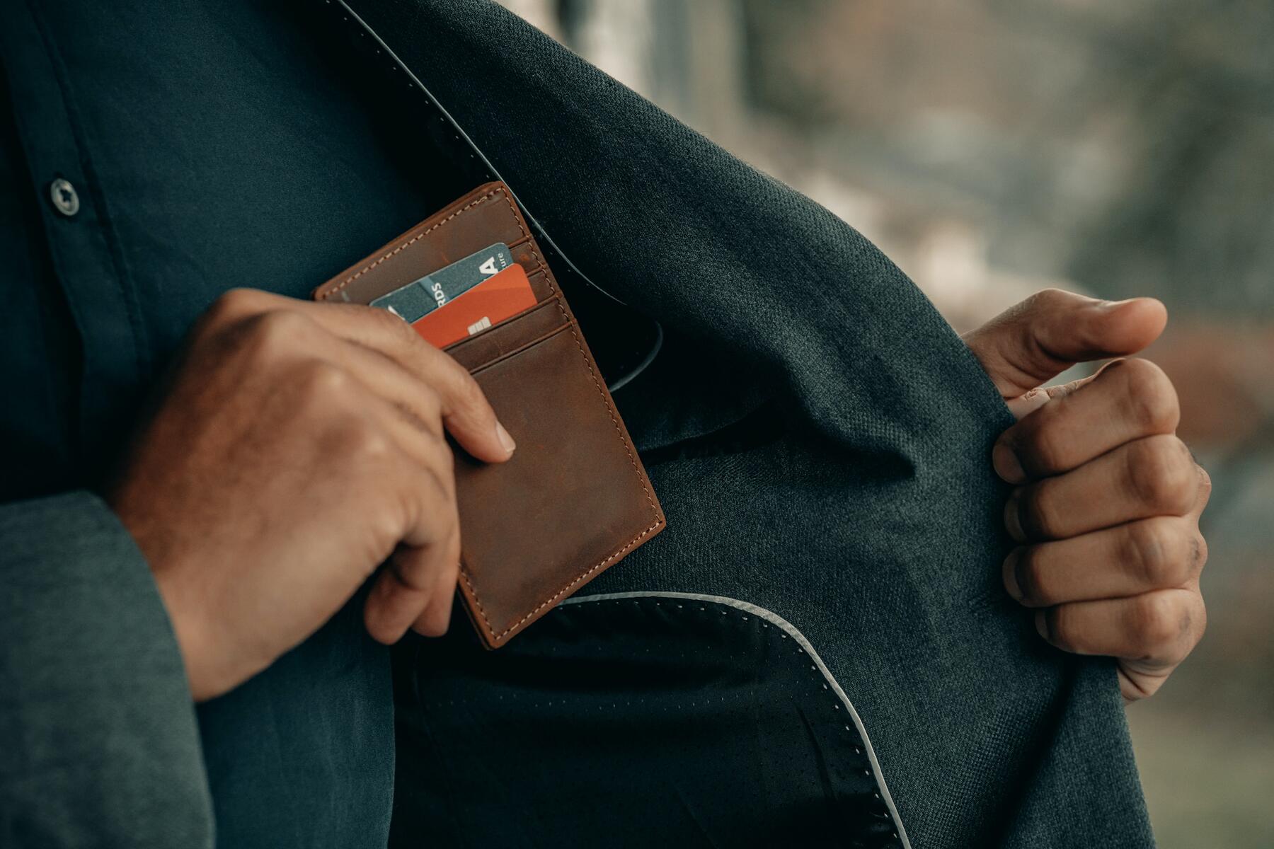 A man sliding a credit card into a wallet pocket