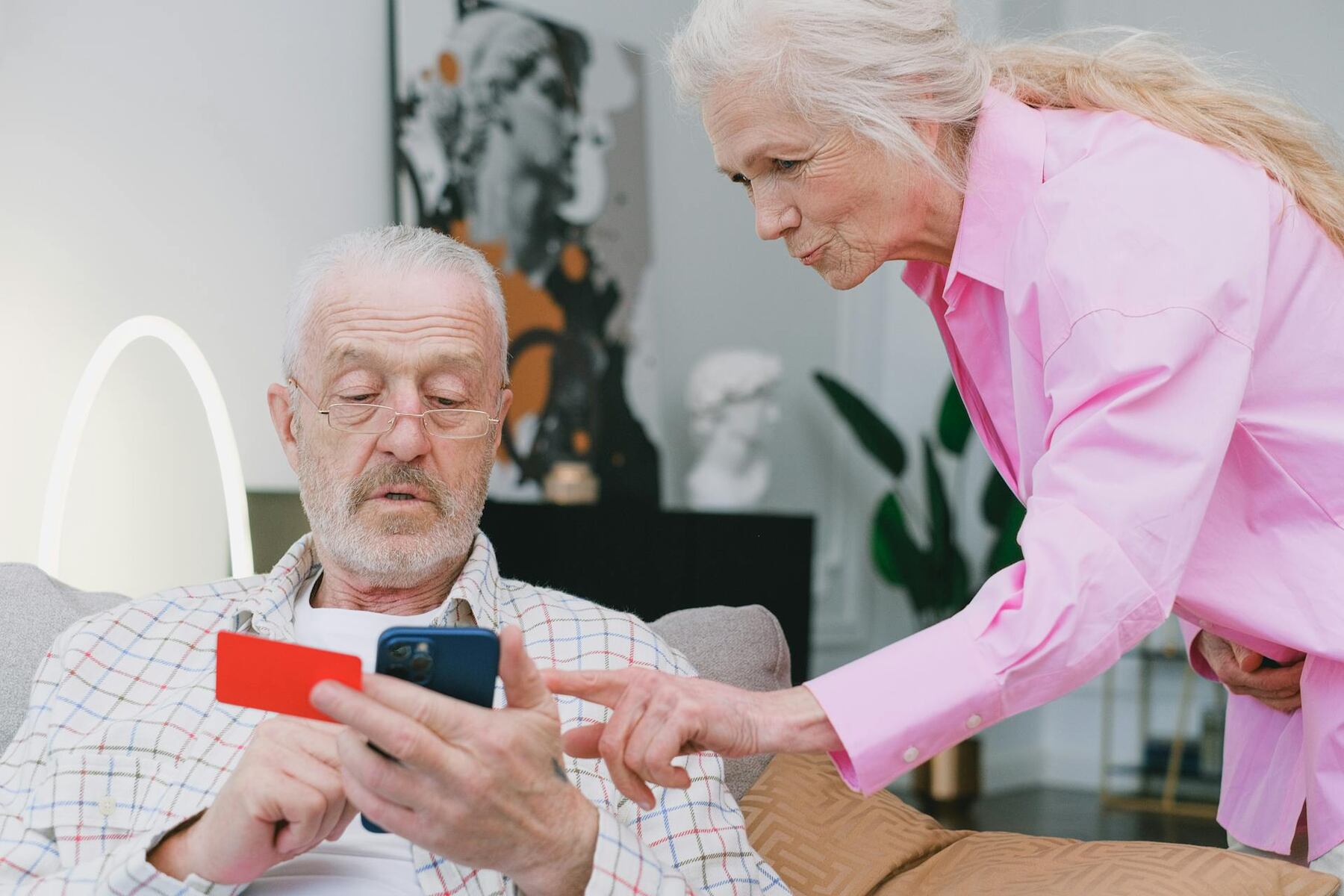 An older man and woman with a smartphone, the woman pointing at the screen