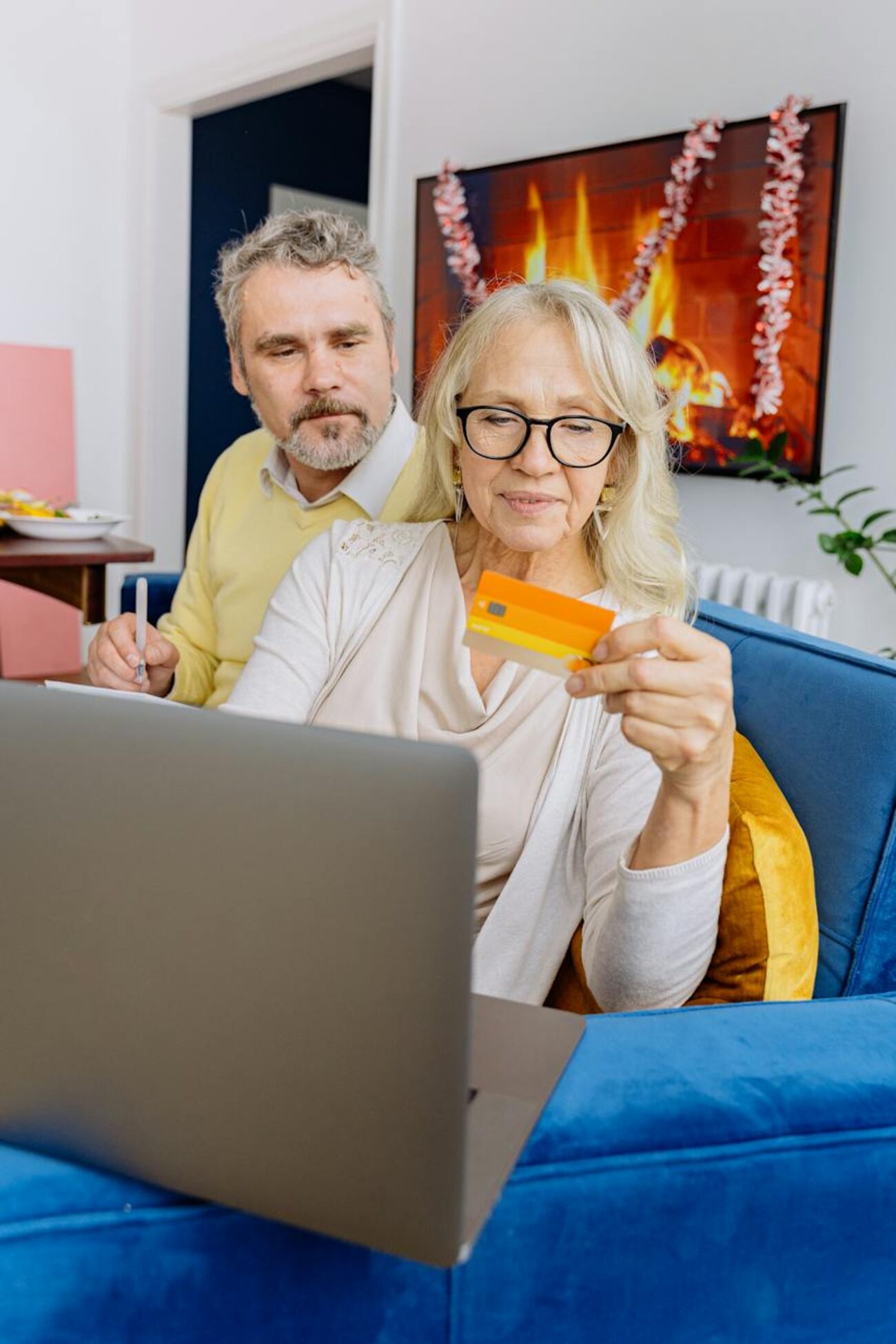A mature couple holding a credit card, with a laptop on their lap