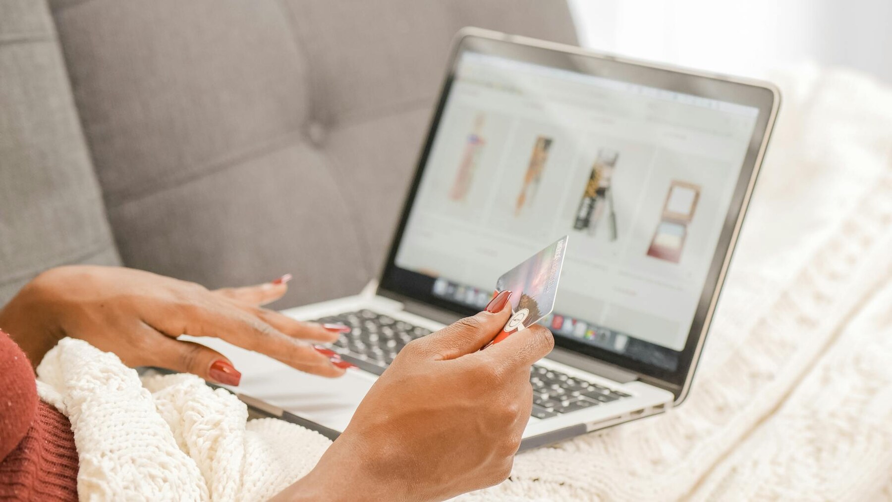 A woman holding a credit card while using a laptop