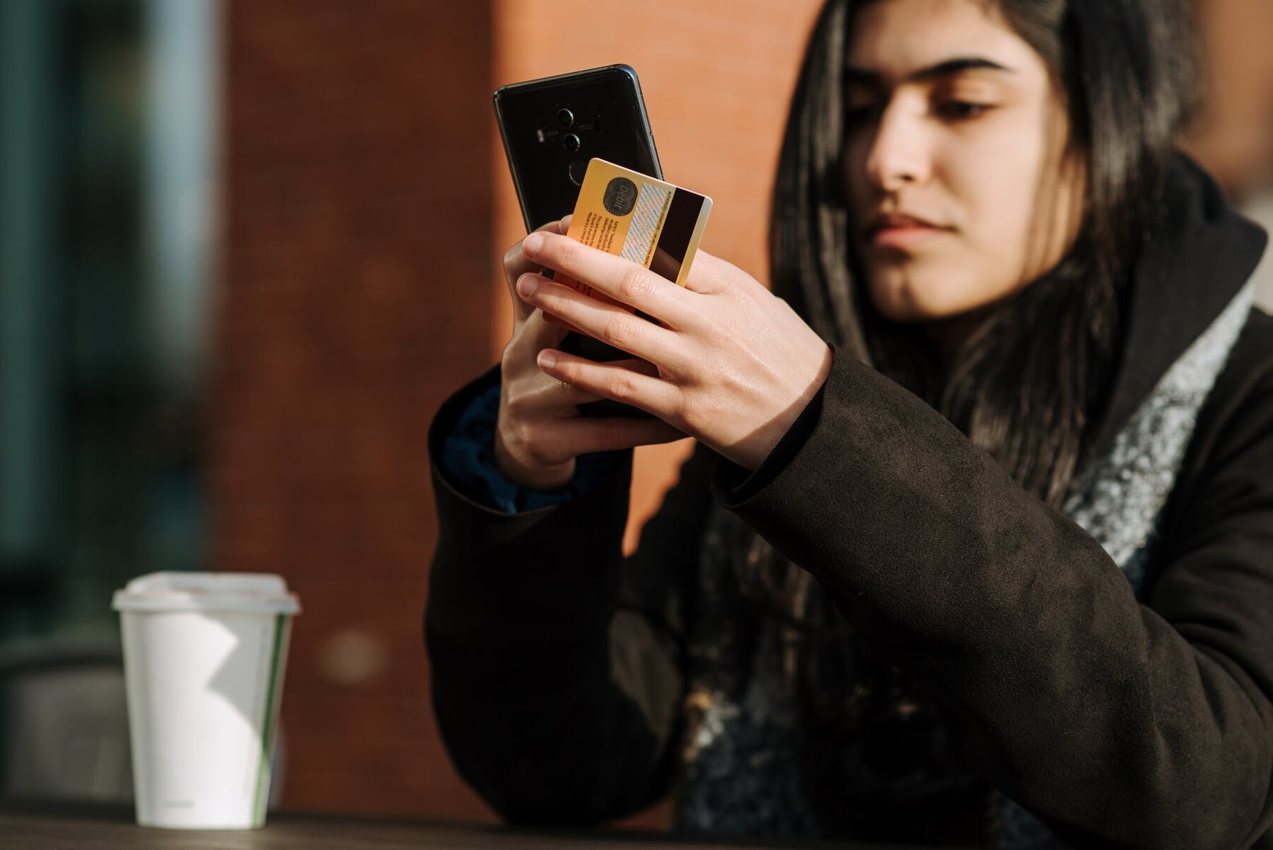 A woman holding a credit card and a smartphone