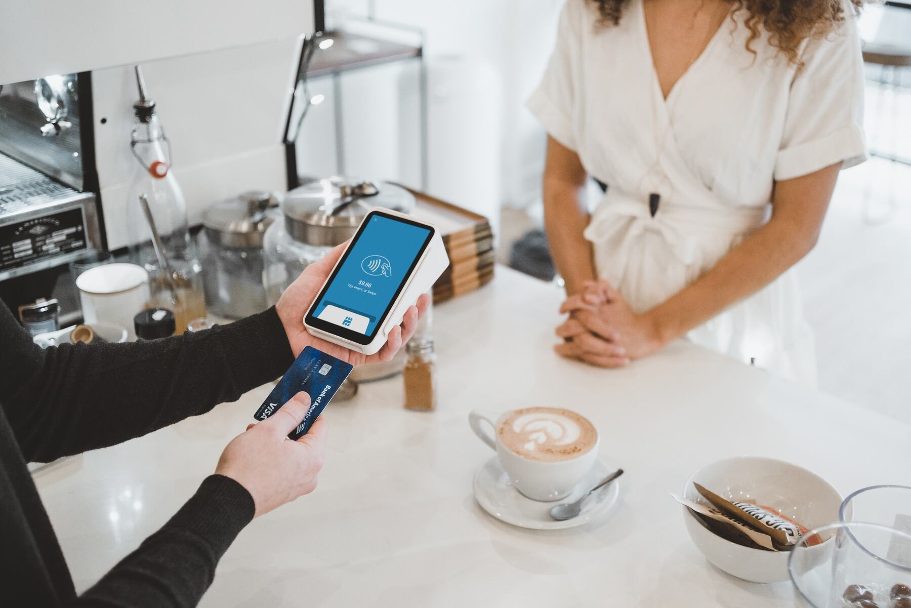 Woman using a portable pay terminal to charge a credit card while a customer looks on