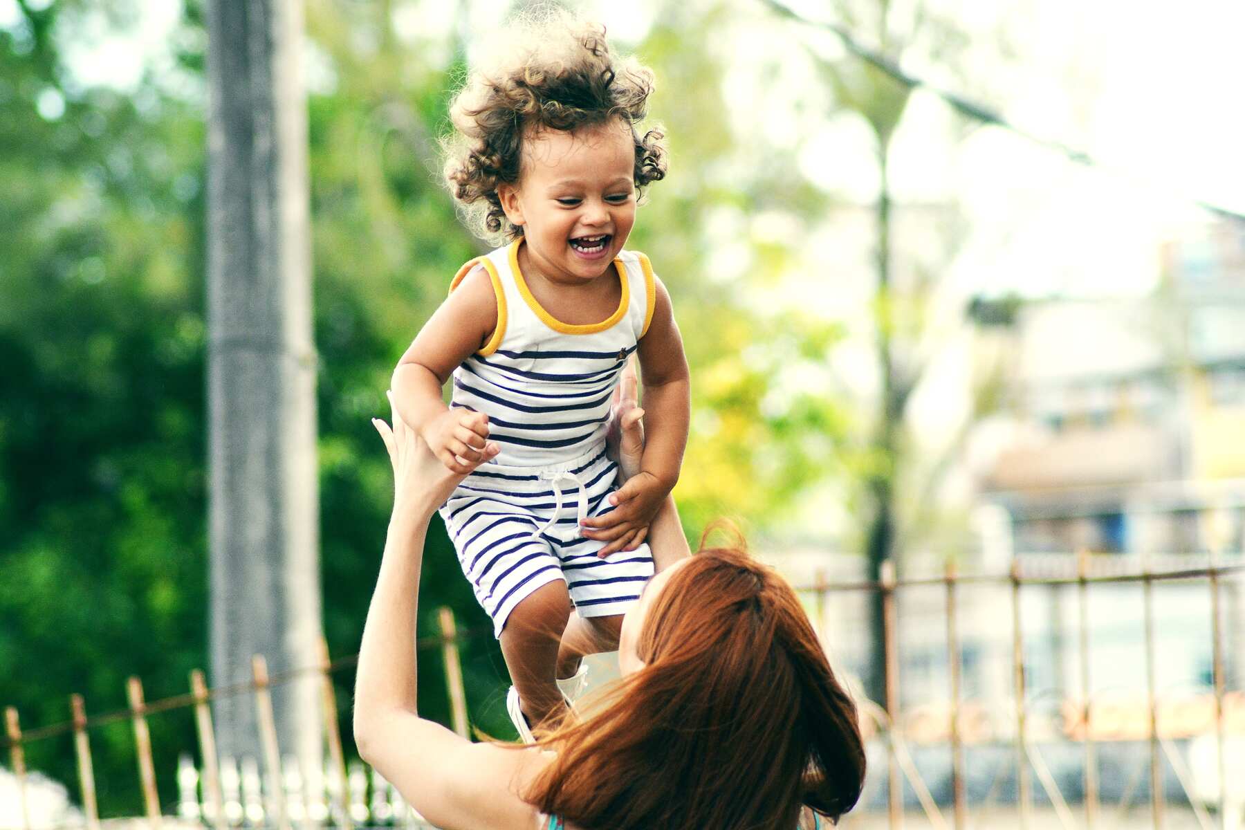 Mom lifting her daughter up during their playtime outdoors