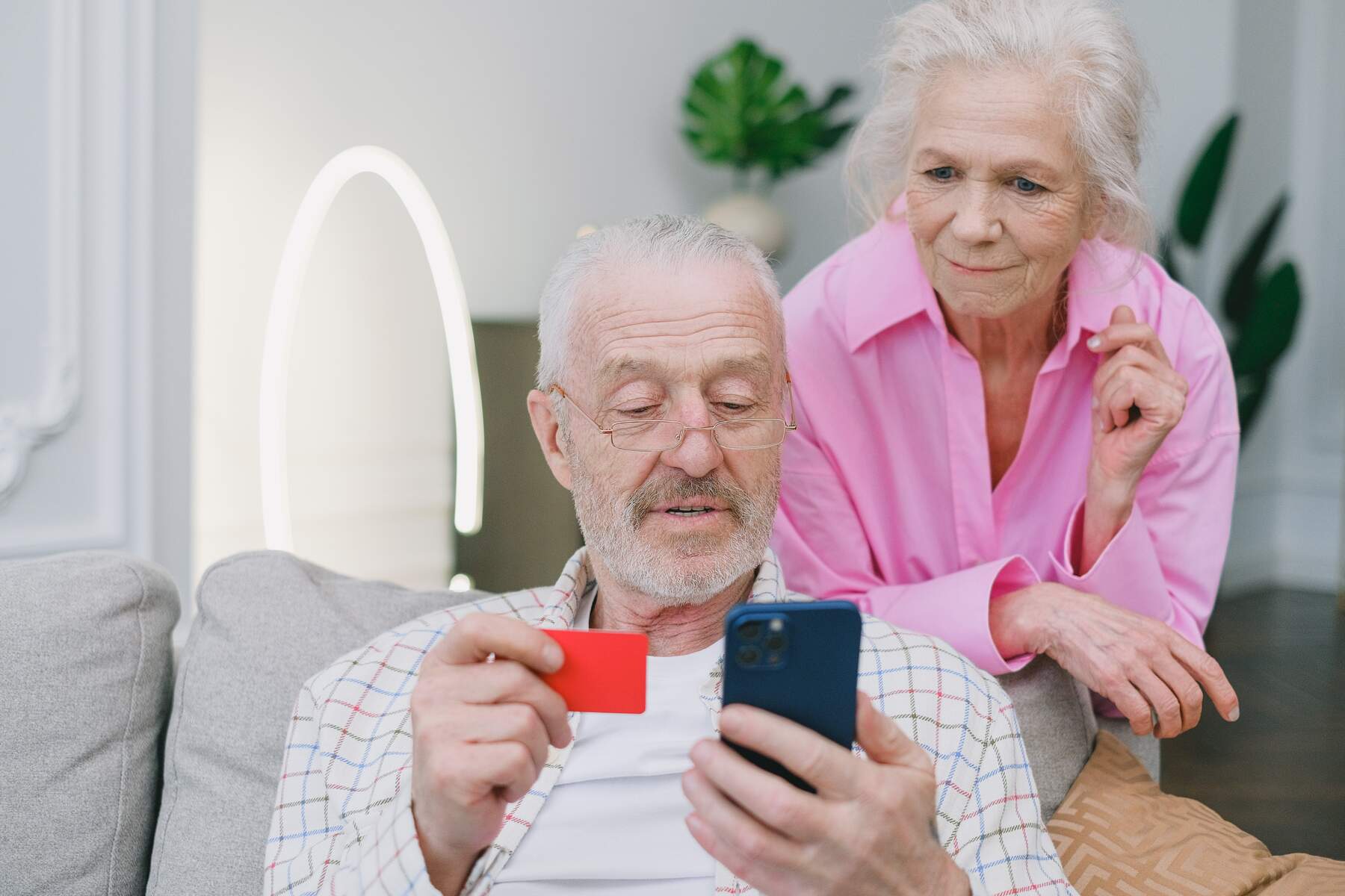 Senior couple shopping through their mobile phone while holding a credit card