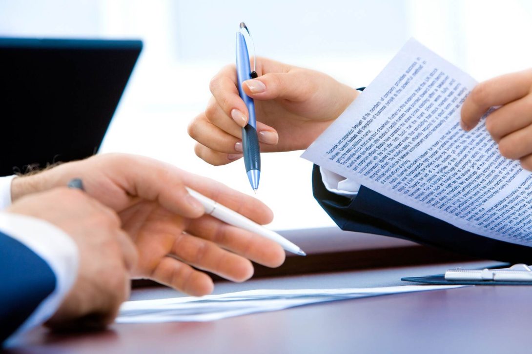 Person pointing with their pens on where to sign on a printed document