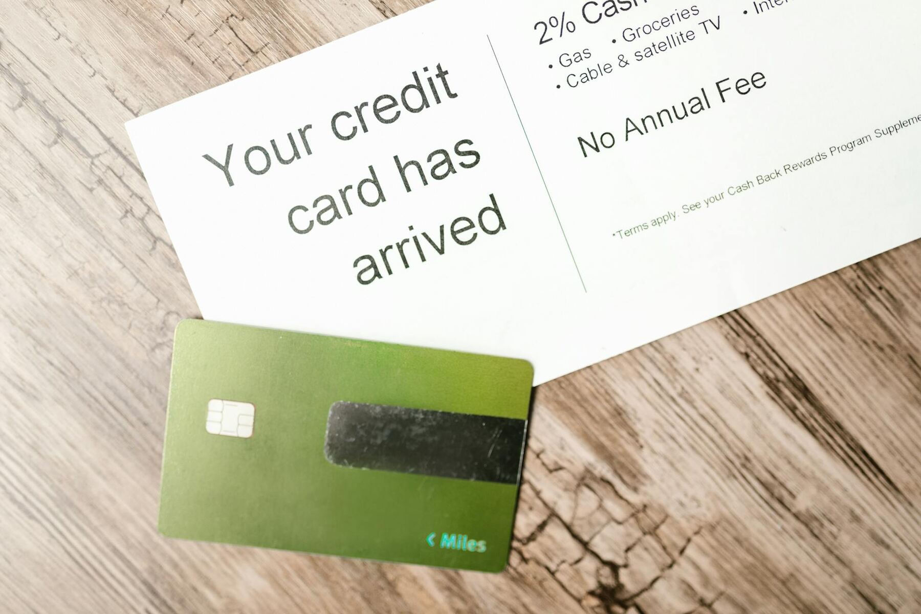 A green credit card beside a welcome letter on a wooden surface