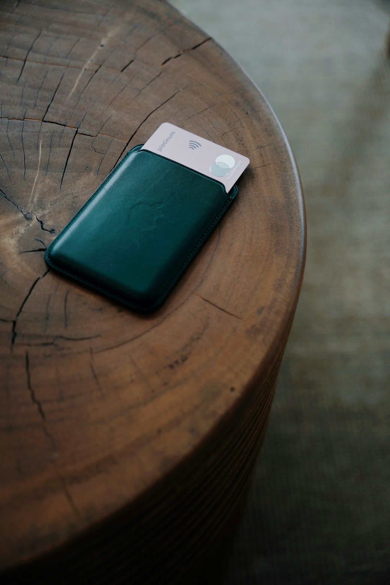 A green wallet with a credit card on a wooden table