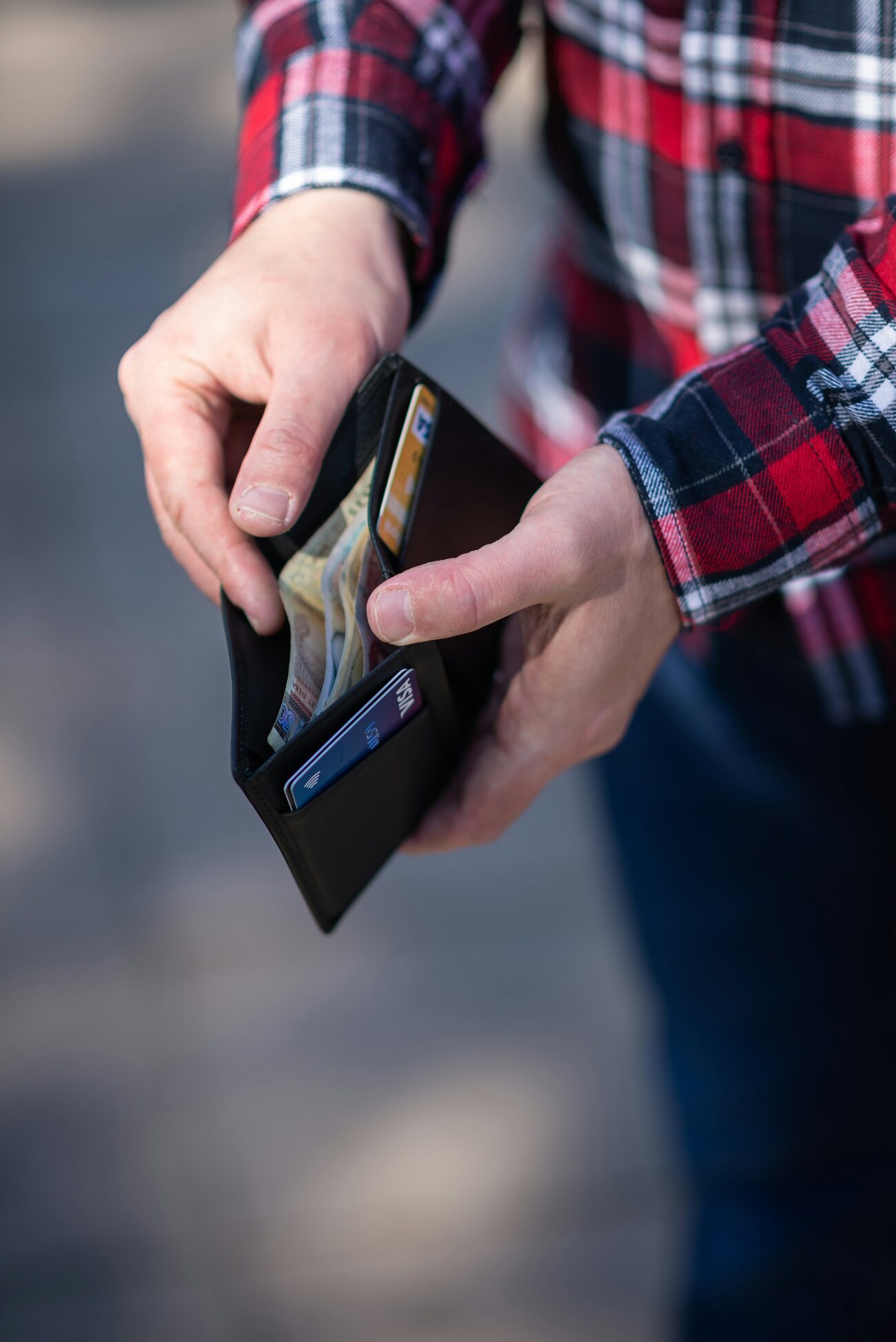 A man taking cash and cards out of a black wallet