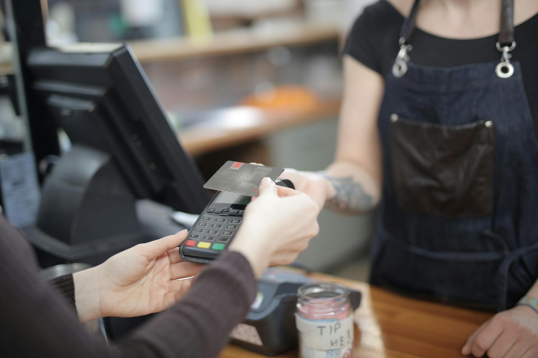 A woman paying a credit card at a cash register using the card reader