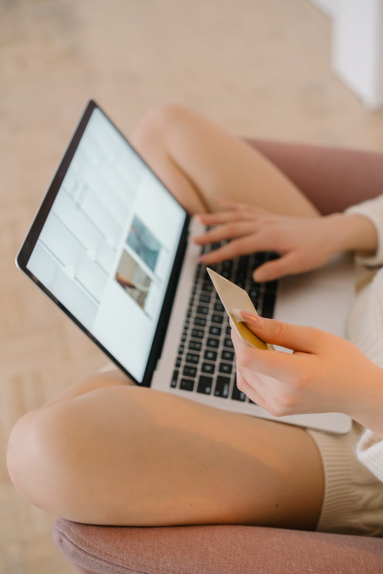 A woman sitting on a chair, using a laptop and holding a credit card to make online purchases