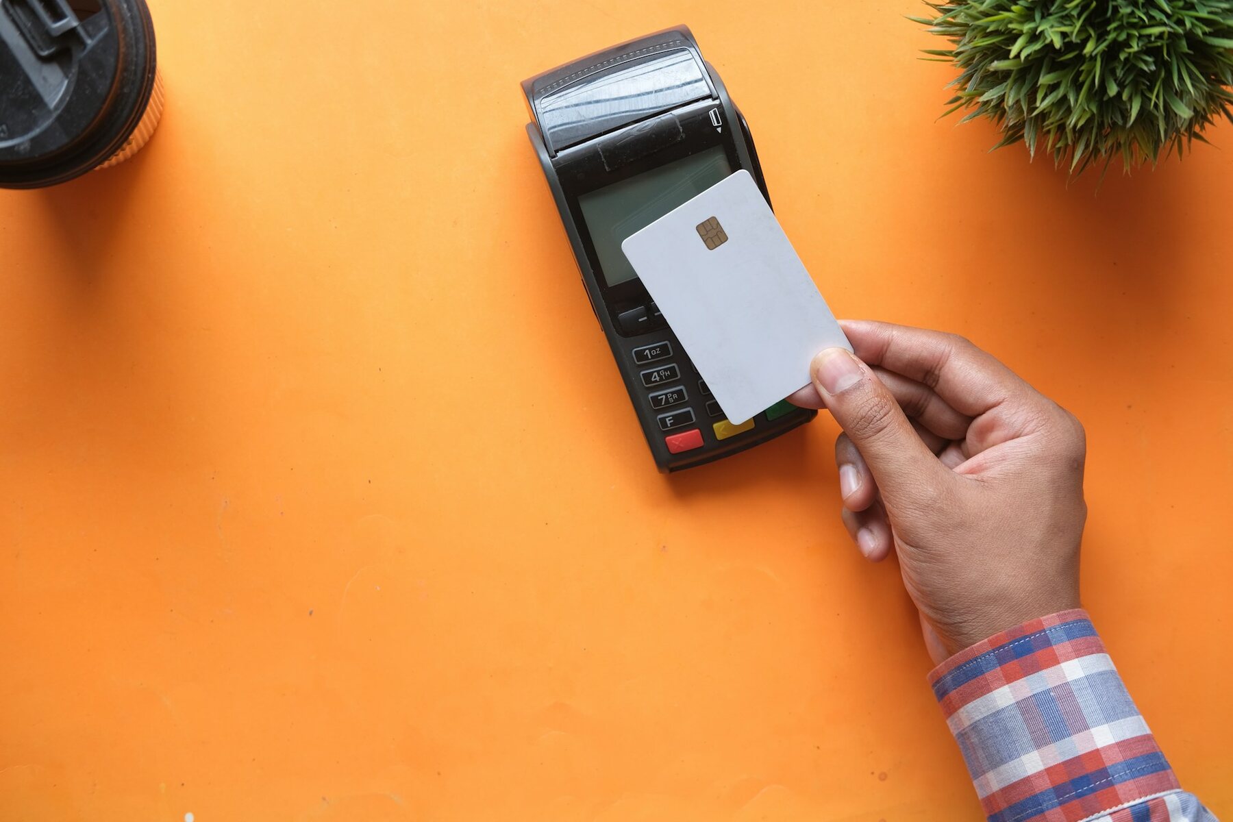Man holding credit card on a card reader against vibrant orange background