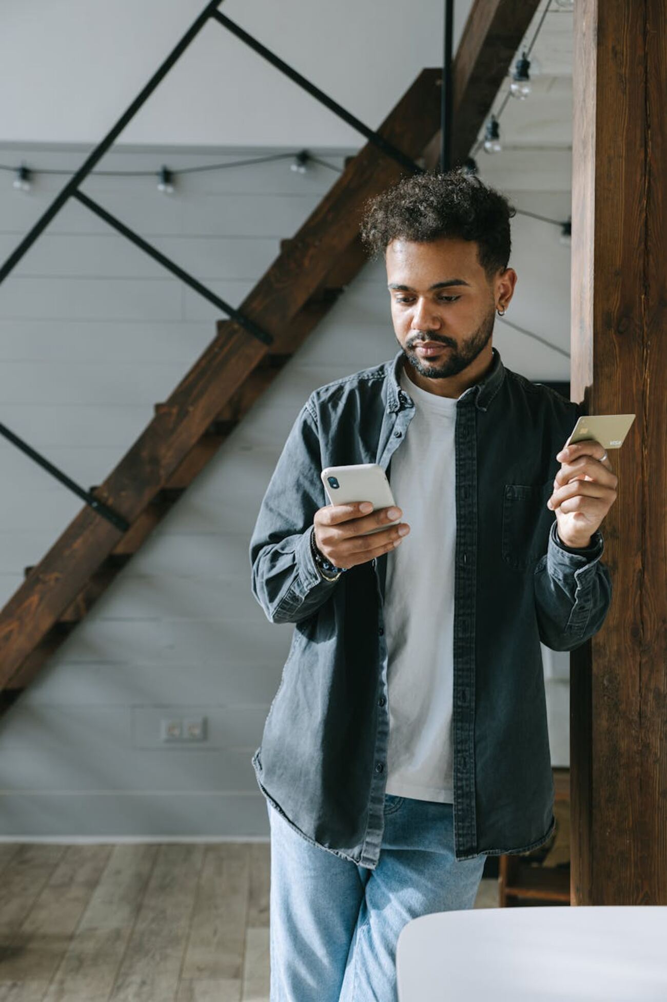 A man making a purchase online with a credit card and phone in a contemporary home setting