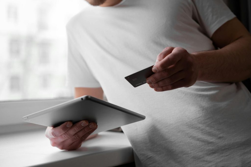A man holding a credit card and using a tablet for online shopping