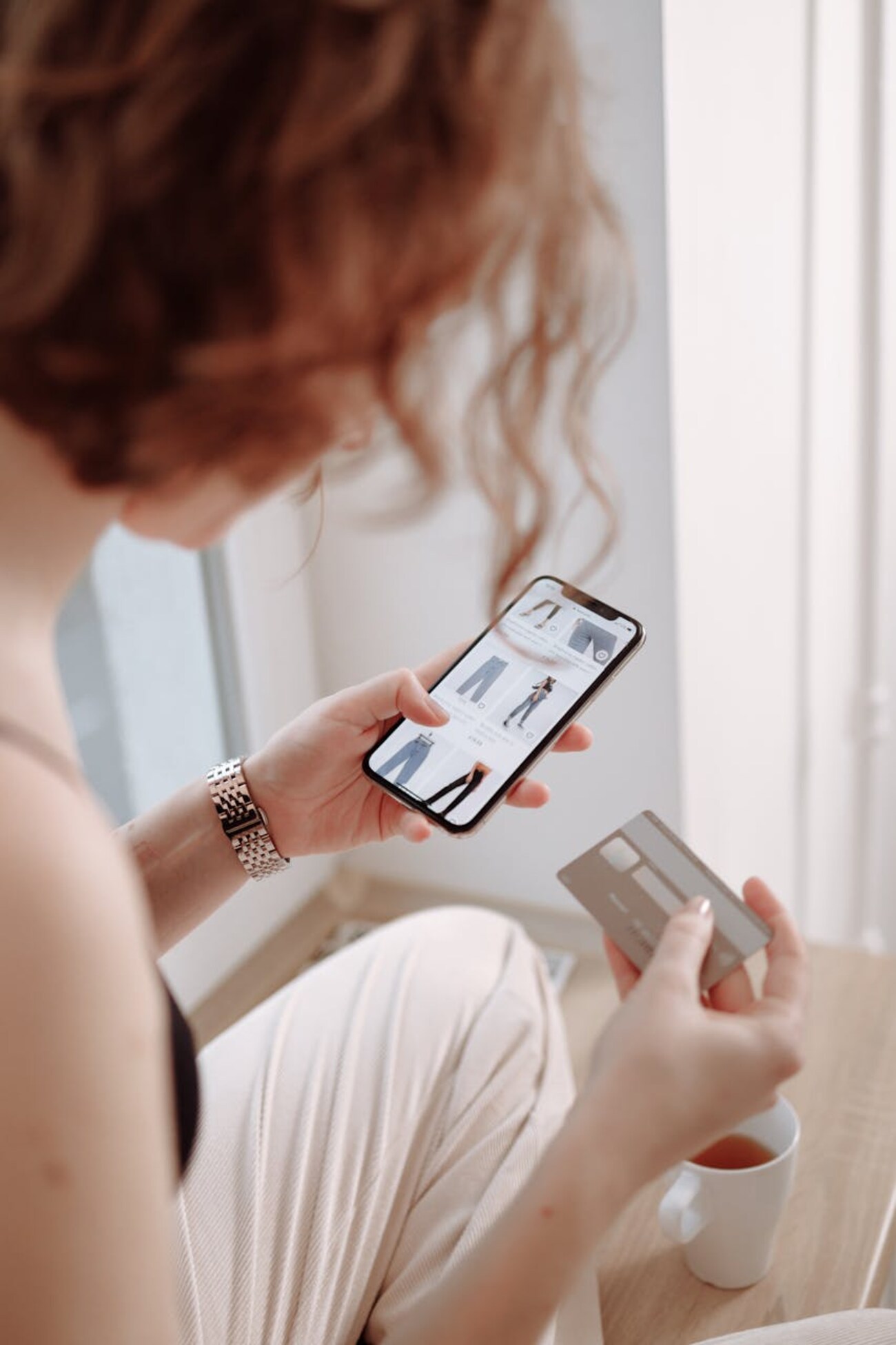 A woman shopping online for products, using a mobile app while holding a credit card