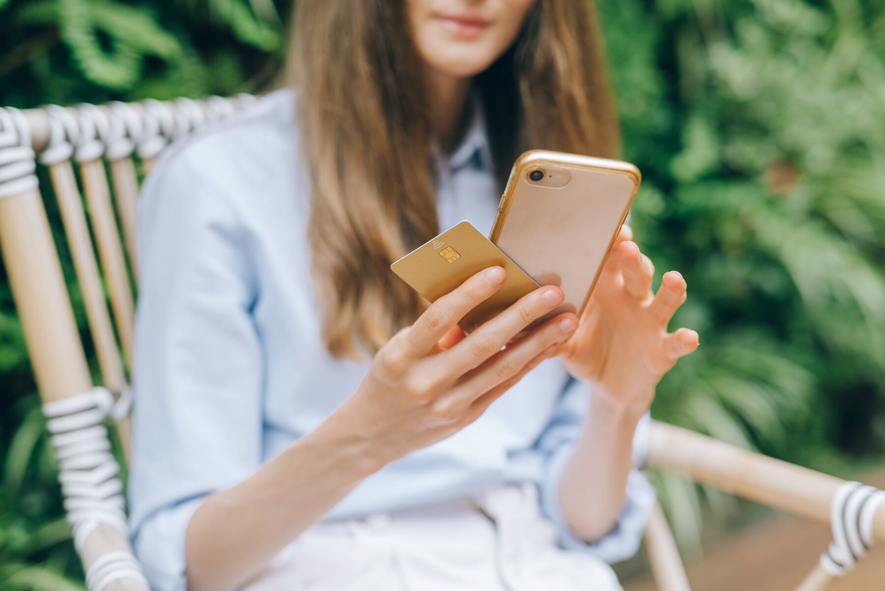 A woman sitting, holding her phone and credit card