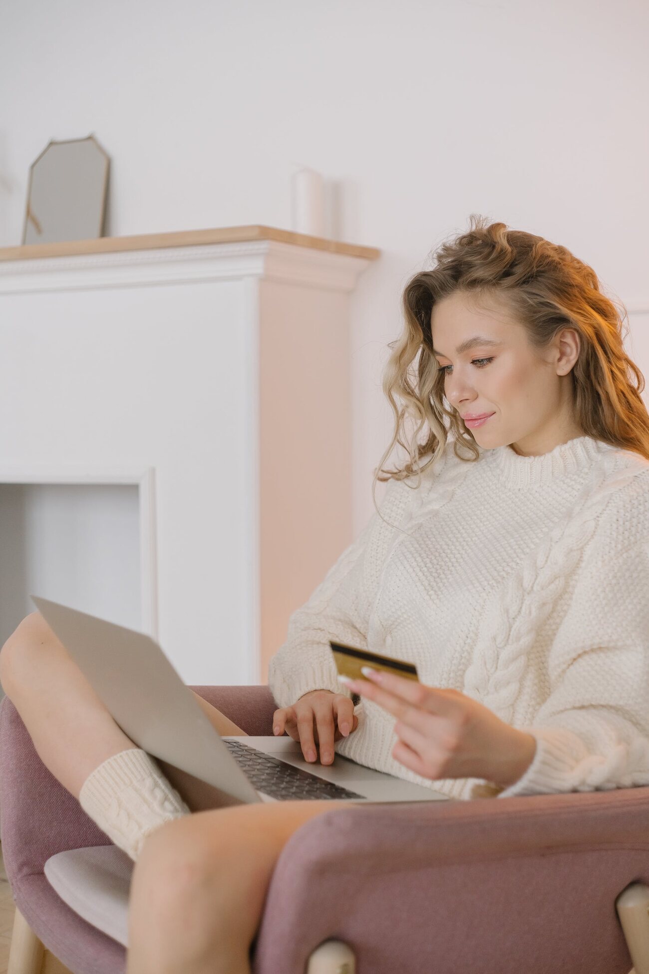 A woman sitting holding a credit card and a laptop on her lap