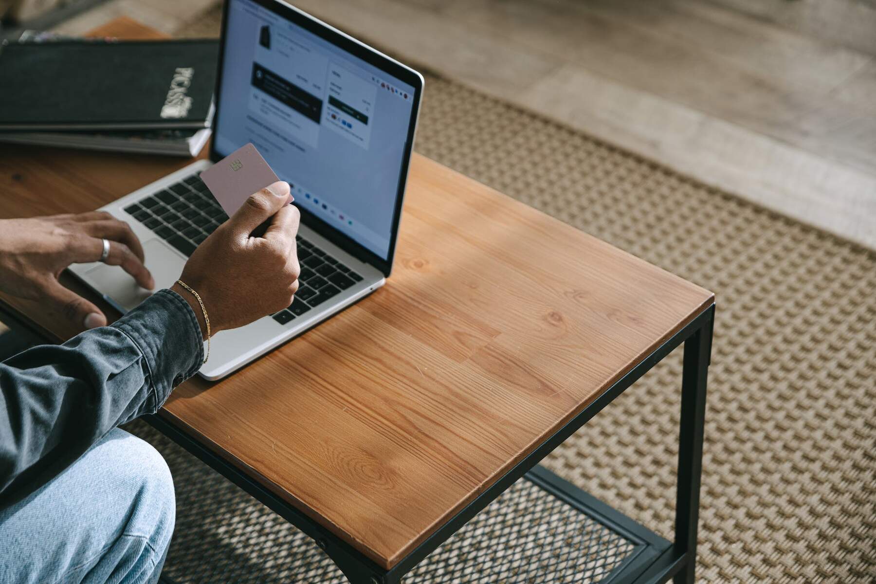 A man holding a credit card while a laptop is on a table