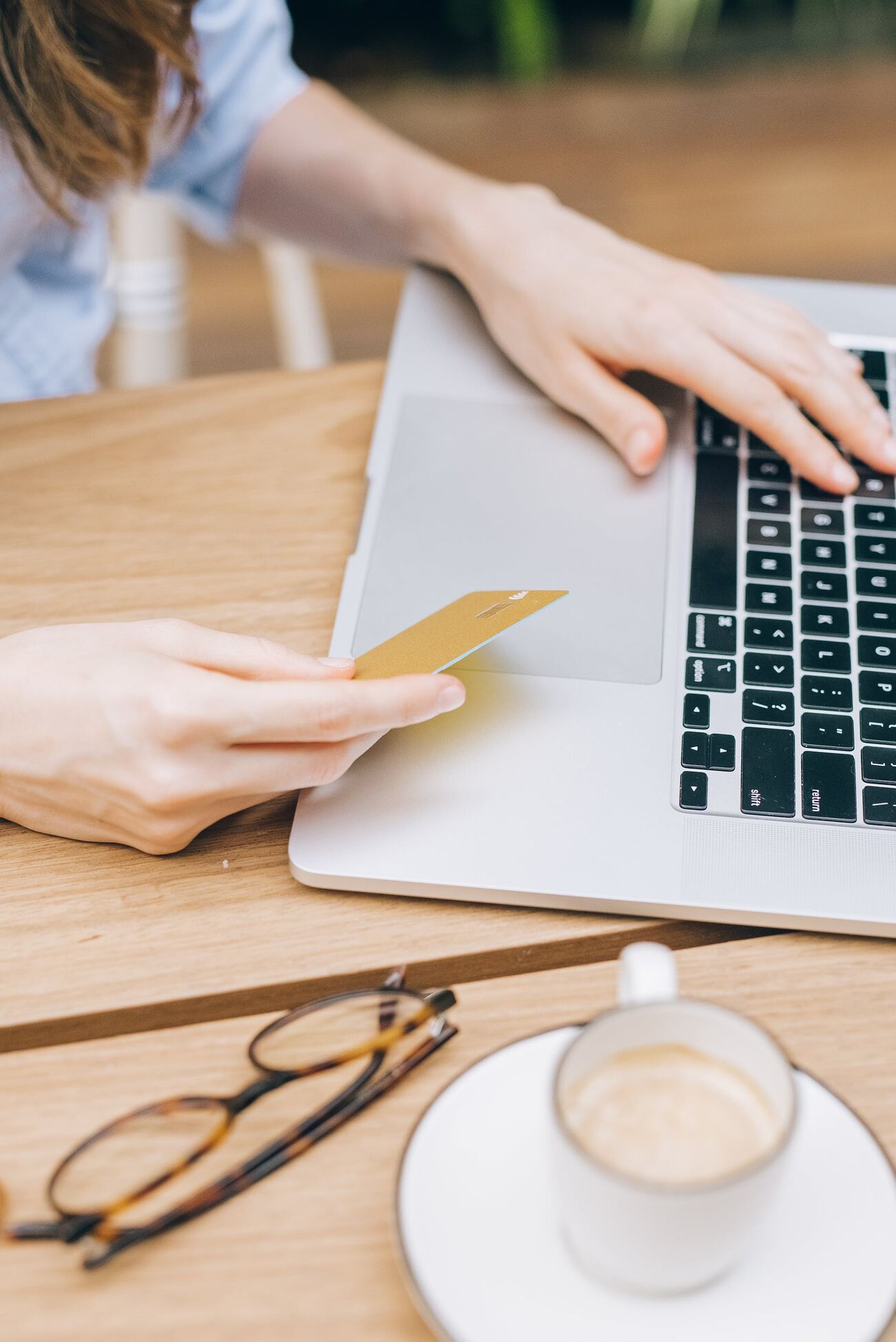 A woman holding her credit card while typing on the laptop