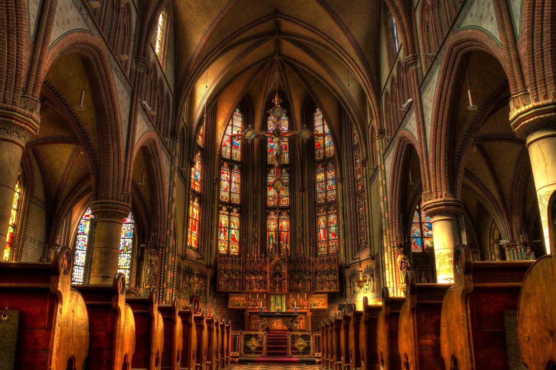 A beautiful church with rows of pews and a colorful stained glass window