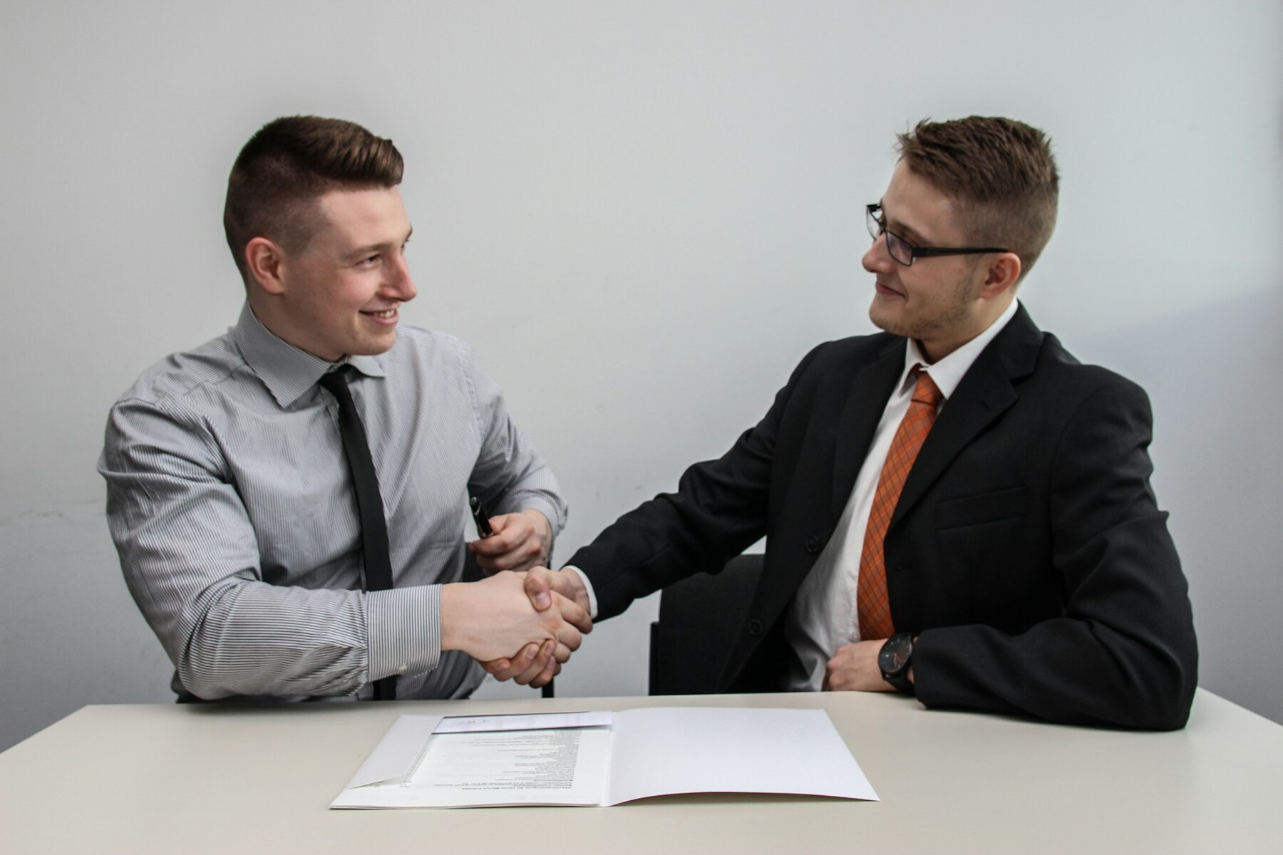 Two businessmen shaking hands at a desk