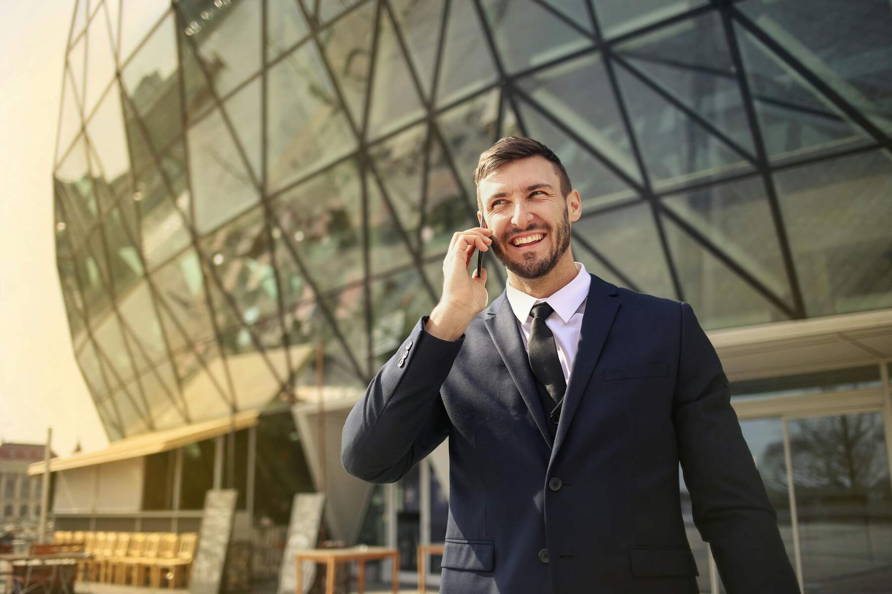 A professional wearing formal attire smiling while talking on his phone