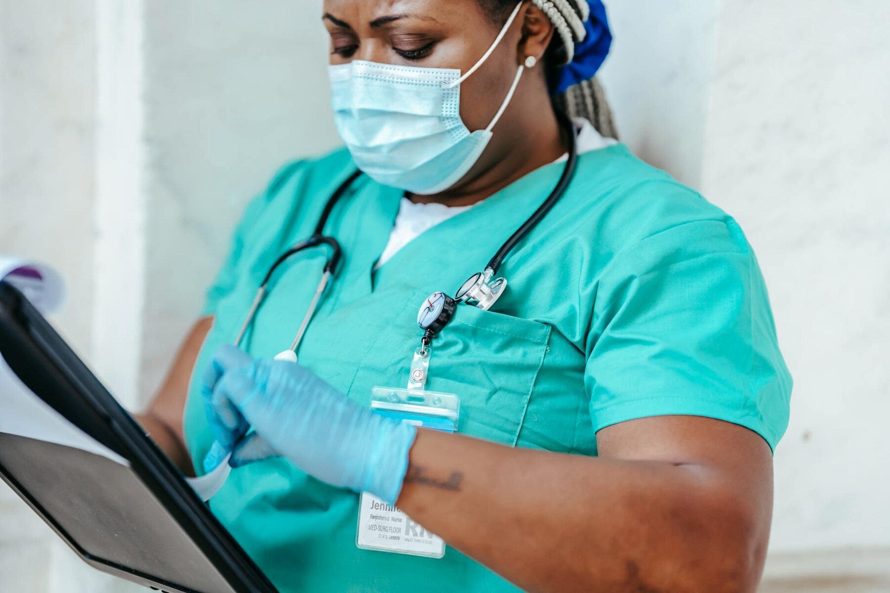 Nurse in green scrubs holding clipboard