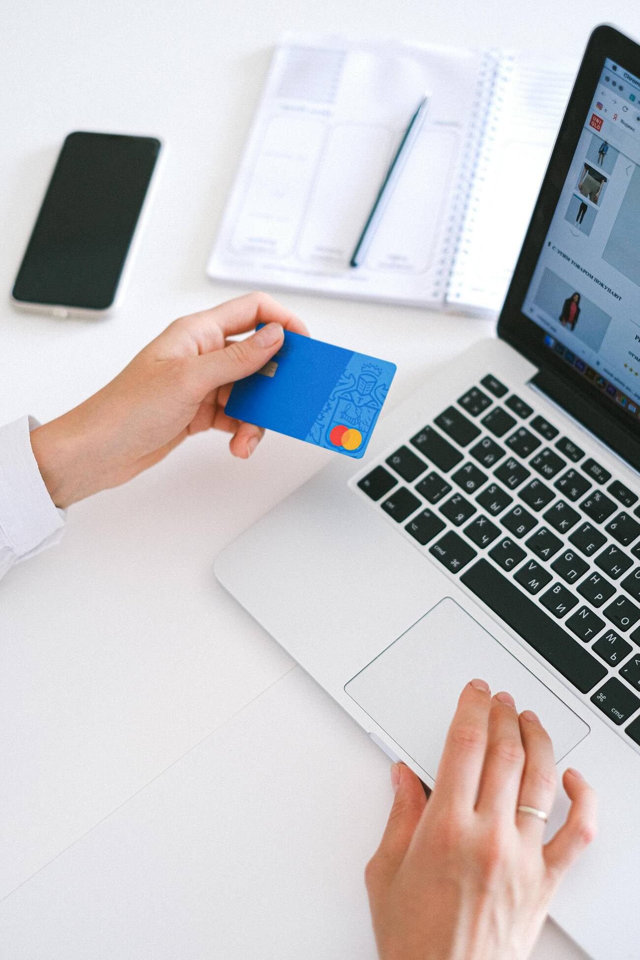 A woman holding a credit in front of a laptop