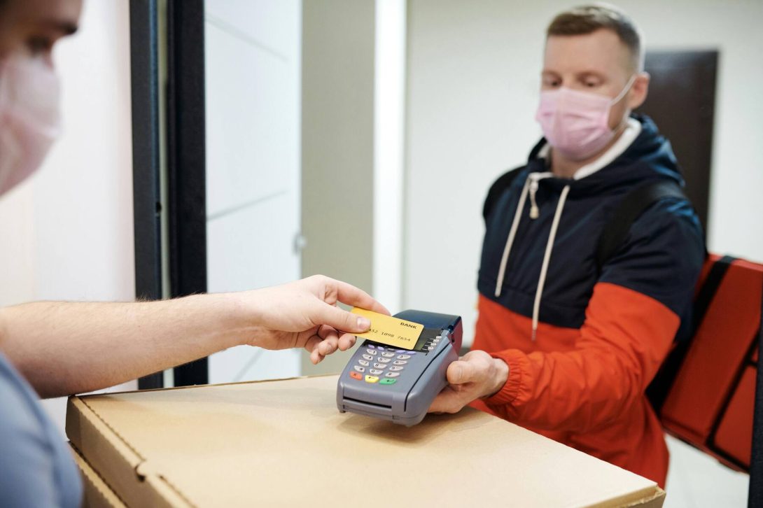 A man swiping his credit card on the delivery man's payment terminal