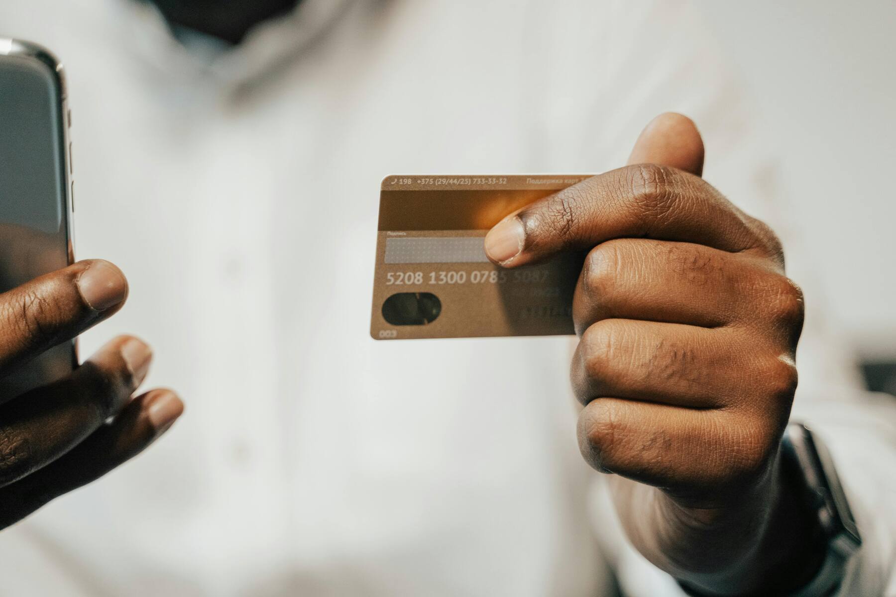 A man holding his credit card and his phone on the other hand