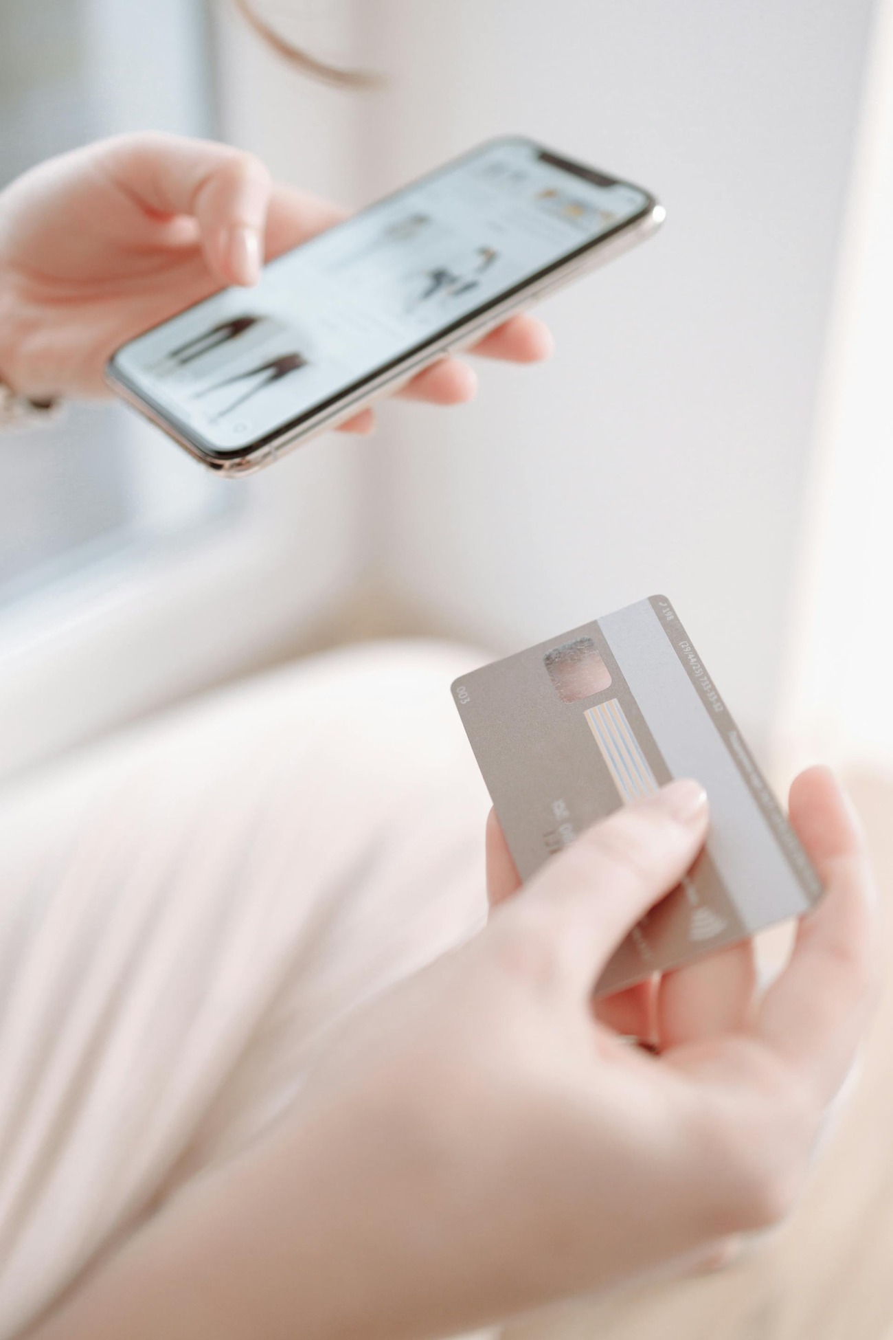 A woman holding a credit card and a smartphone