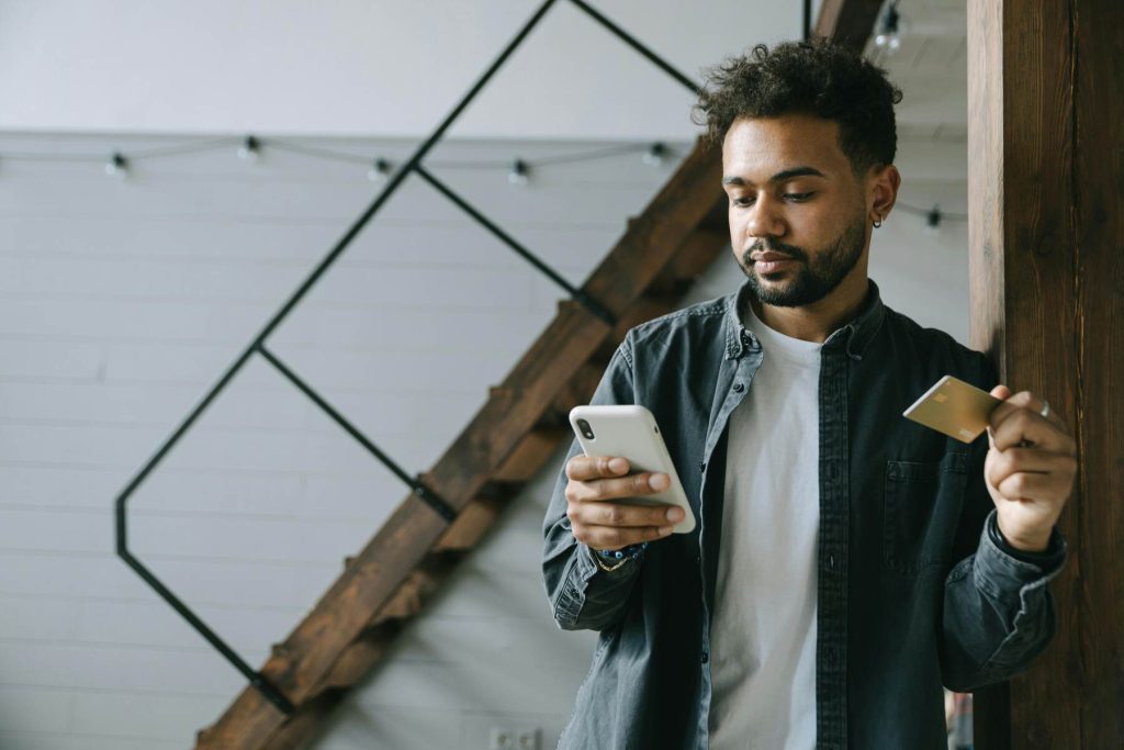 A man using his phone while holding his credit card