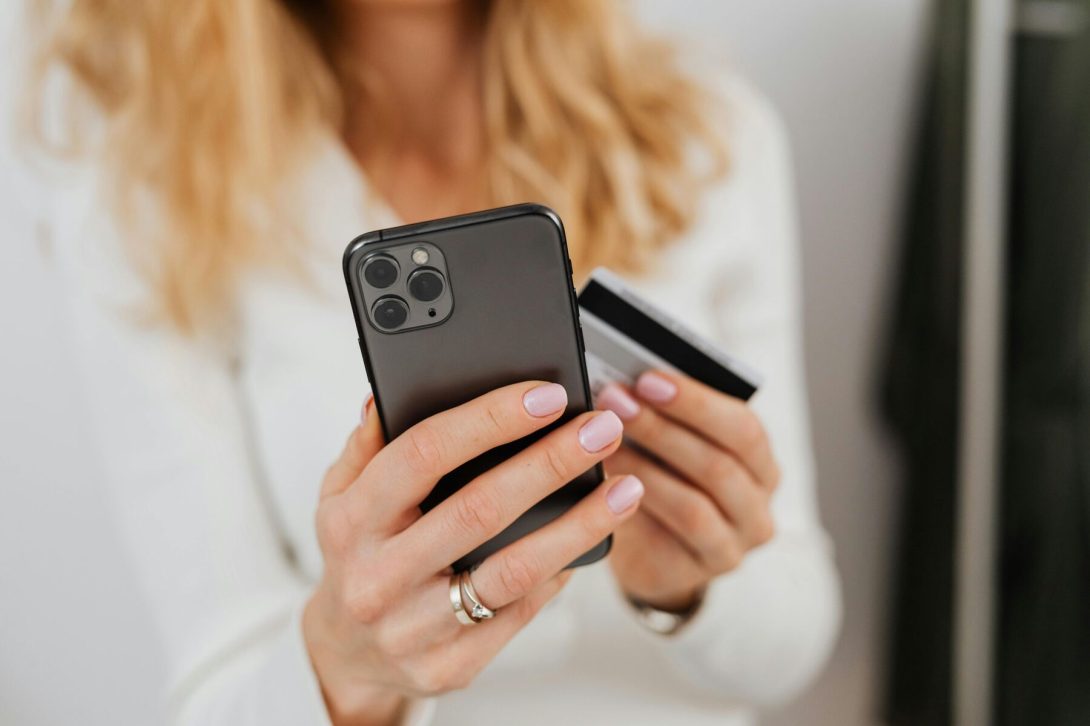 A woman holding her phone and credit card