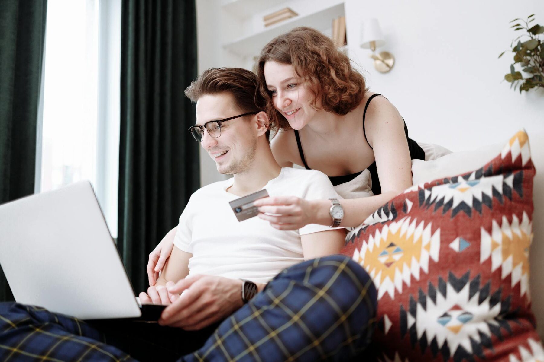 A couple sitting on a couch, using a laptop together