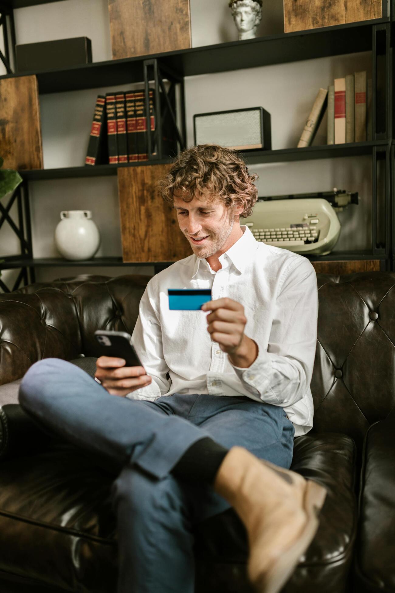 A man sitting on a sofa, using a credit card for a transaction