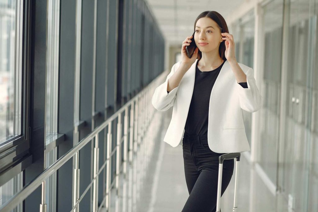 A woman calling someone on her phone while on the airport