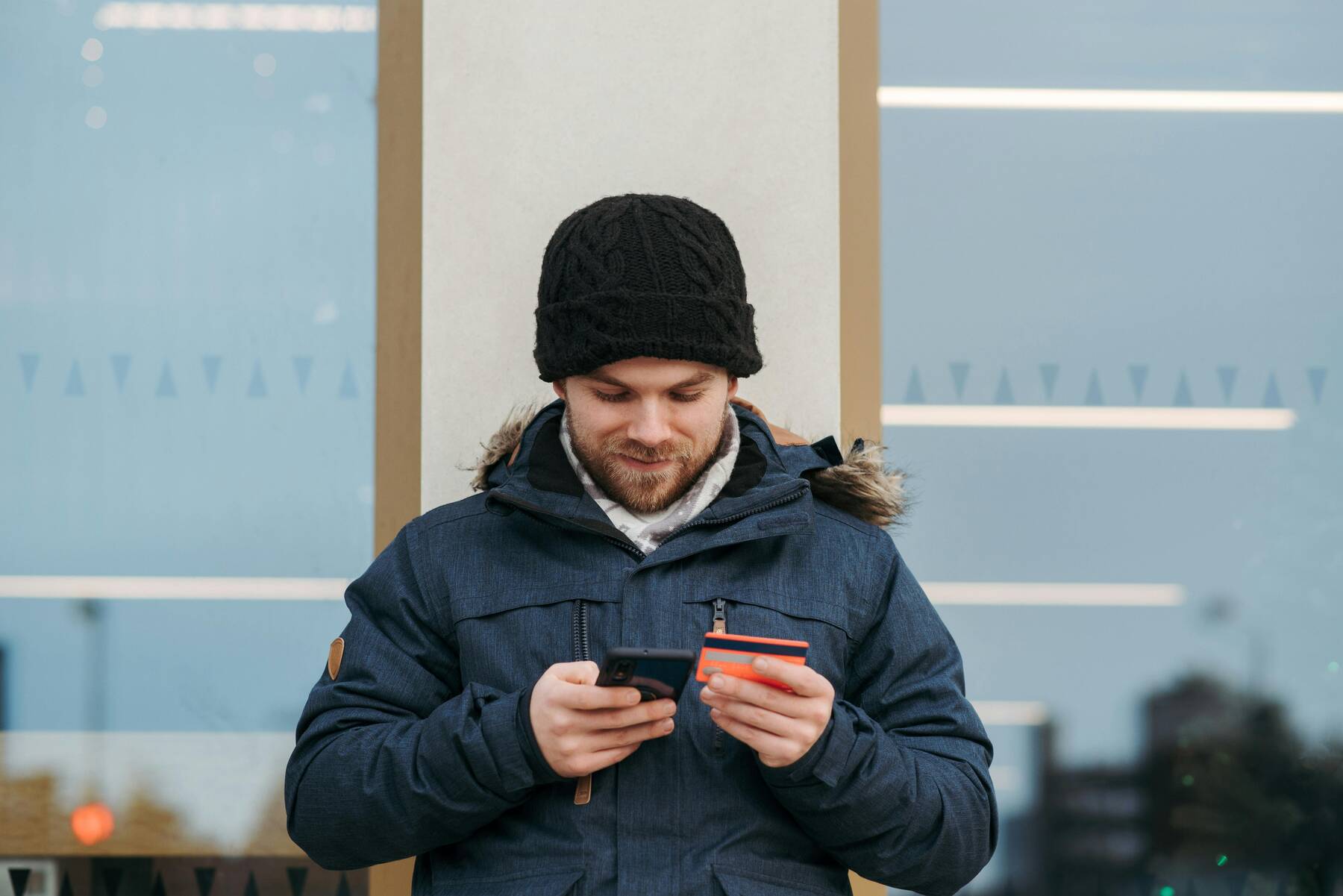 A man outside holding his phone and credit card