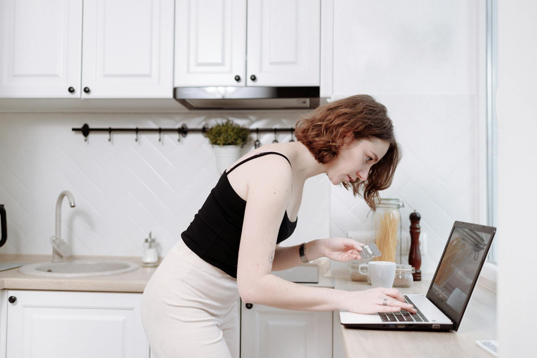 A woman in a black top focused on her laptop screen